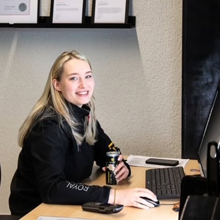 Eine blonde Frau sitzt lächelnd an einem Schreibtisch